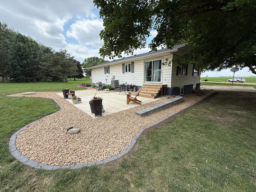 Charming house exterior with landscaped garden, patio area, and outdoor seating by trees.