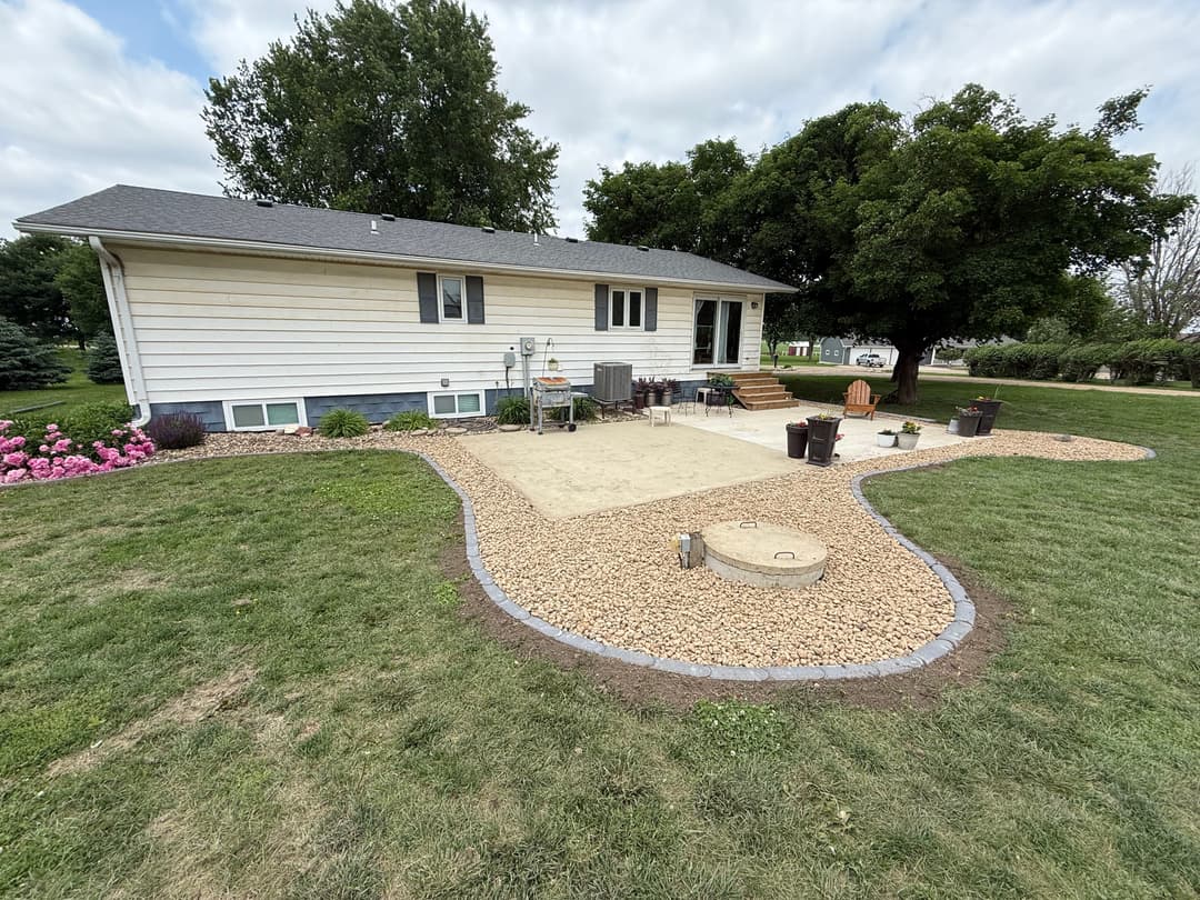 Home exterior with landscaped yard, patio area, and fire pit surrounded by decorative stones.