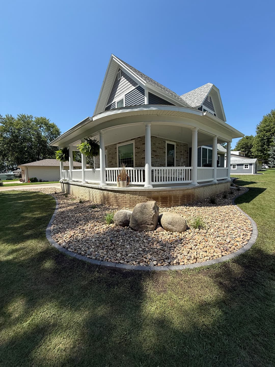 Charming house with porch, landscaped stones, and a clear blue sky in the background.