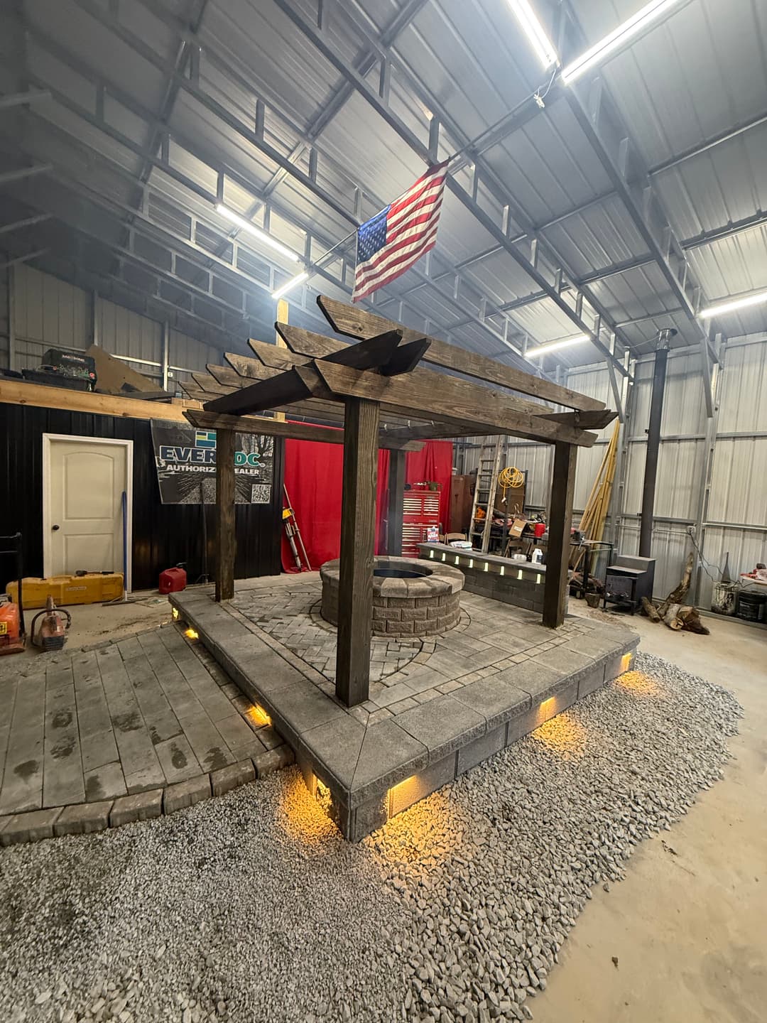 Outdoor pergola with stone seating area and gravel, illuminated by built-in lights.