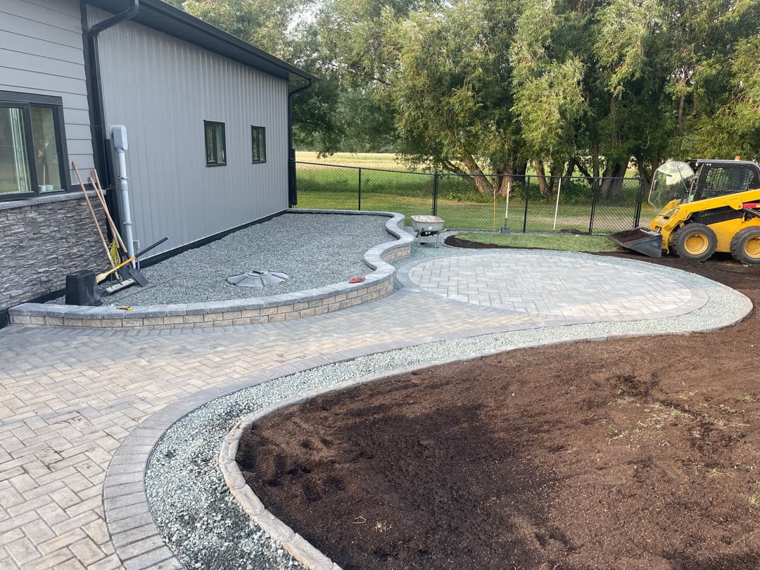 Landscape design featuring a newly paved patio, gravel path, and outdoor equipment.